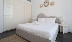 Ein modernes Schlafzimmer mit einem großen Bett, zwei Nachttischen und einem Kleiderschrank.