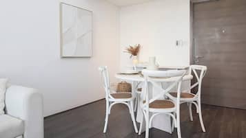 Comedor con una mesa redonda, sillas blancas y piso de madera oscura.