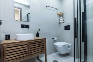 A modern bathroom with a wooden vanity, a white sink, a toilet, and a glass shower enclosure. - Acropolis View Deluxe Suite with Balcony (Athens)