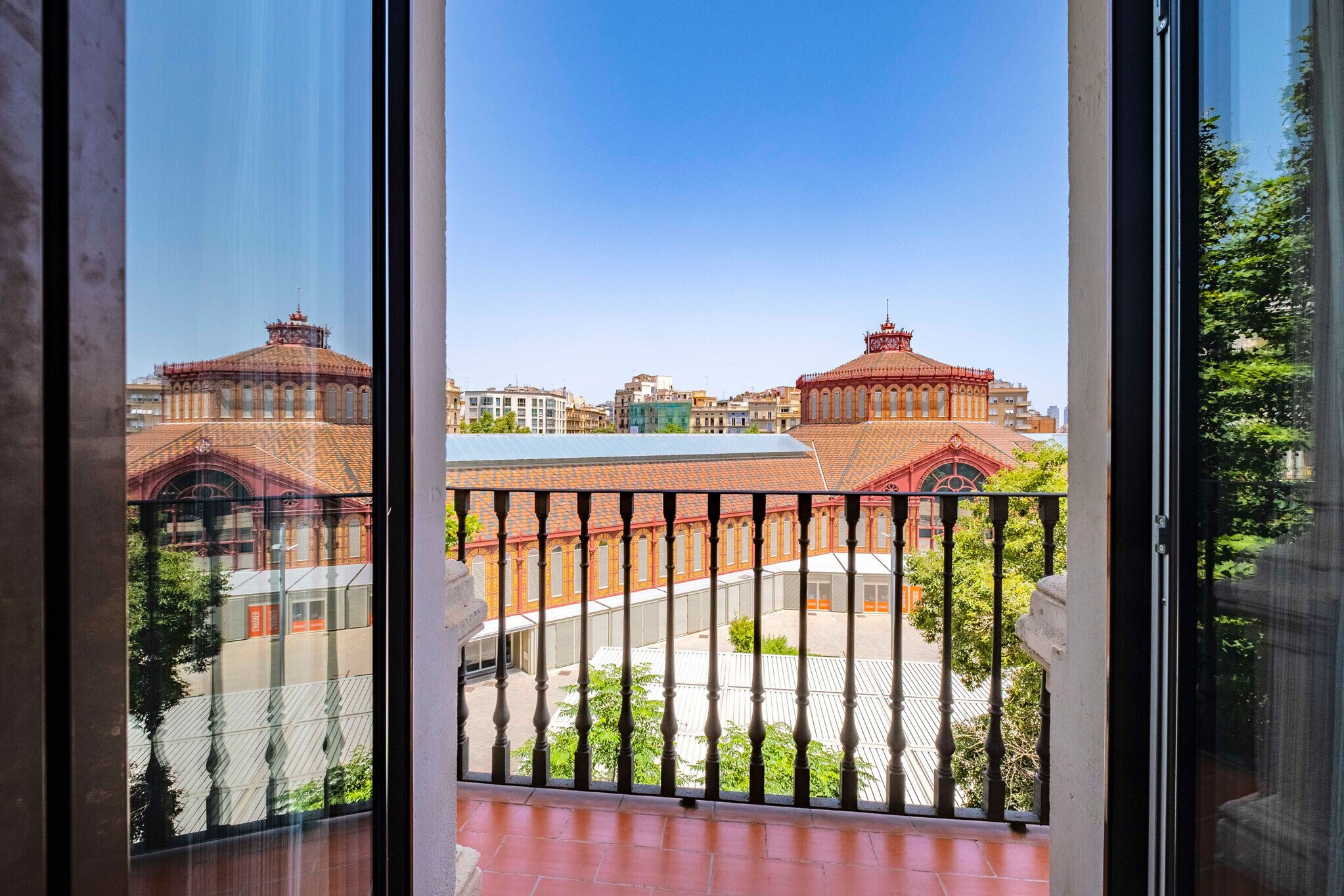 Uma varanda com vista para um edifício de telhado assimétrico e uma torre do relógio.