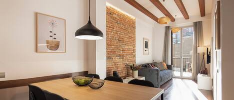 A modern dining area with a wooden table, black chairs, and a brick wall.