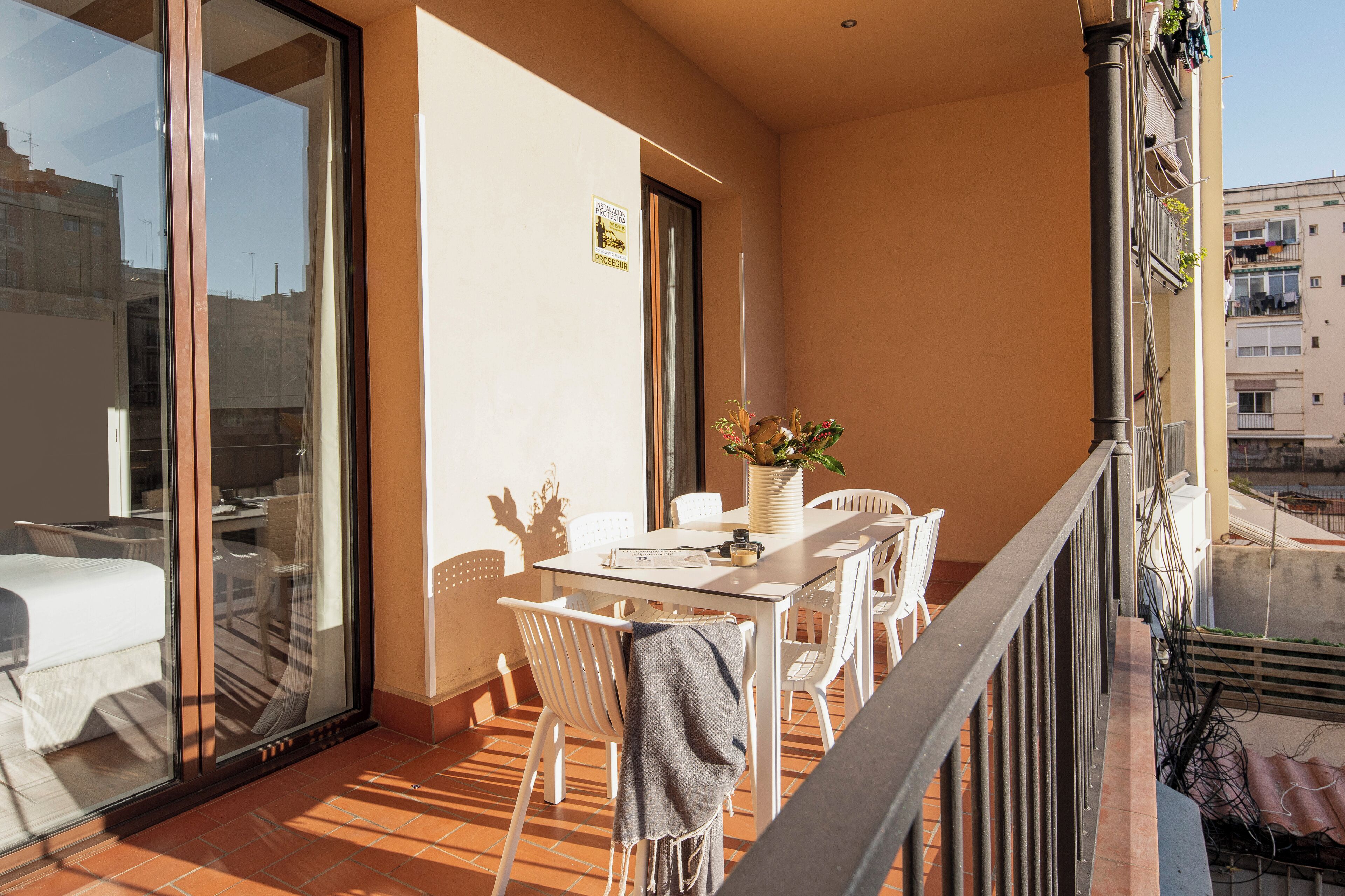 A balcony with a table and chairs, a potted plant, and a view of the city.