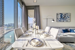 Enjoy a stylish space with a dining area and living space, featuring a round table and a sofa with a city view.