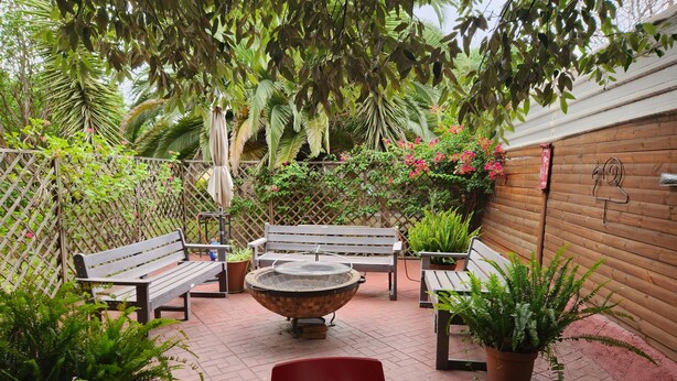 An outdoor patio with wooden benches, a fire pit, and potted plants. - St Michelle Guest Lodge (Alberton)
