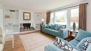 A modern living room with a fireplace, a sofa set, and a dining area.