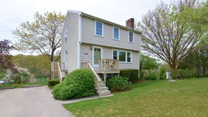 A two-story house with a front porch, a small deck, and a mailbox.