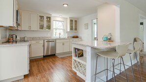 A modern kitchen with white cabinets, stainless steel appliances, and a marble countertop.