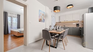 Cocina moderna con comedor, una cama en la habitación contigua y vistas a través de una ventana con cortinas.