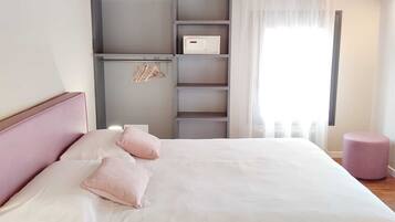 Una camera da letto con un letto, un armadio, uno sgabello e una finestra con tende.