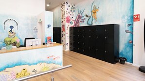 A reception area with a mural of an underwater scene, a reception desk, and black lockers. - Adventure Hostel Madrid Gran vía (Madrid)