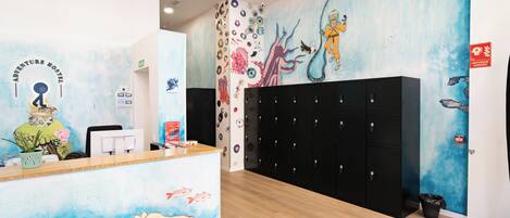 A reception area with a mural of an underwater scene, a reception desk, and black lockers.