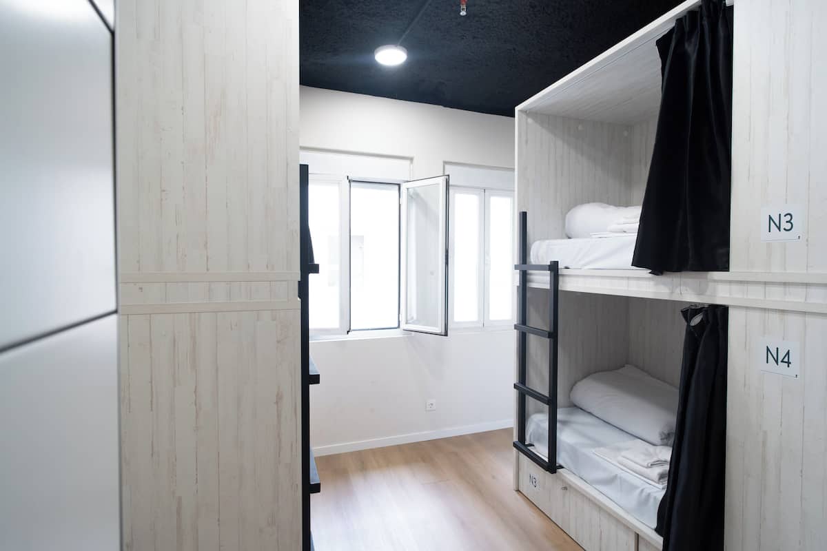 Ein Schlafsaalzimmer mit Stockbetten, die mit N3 und N4 beschriftet sind, Holzwänden, einem Fenster und einer Deckenleuchte.