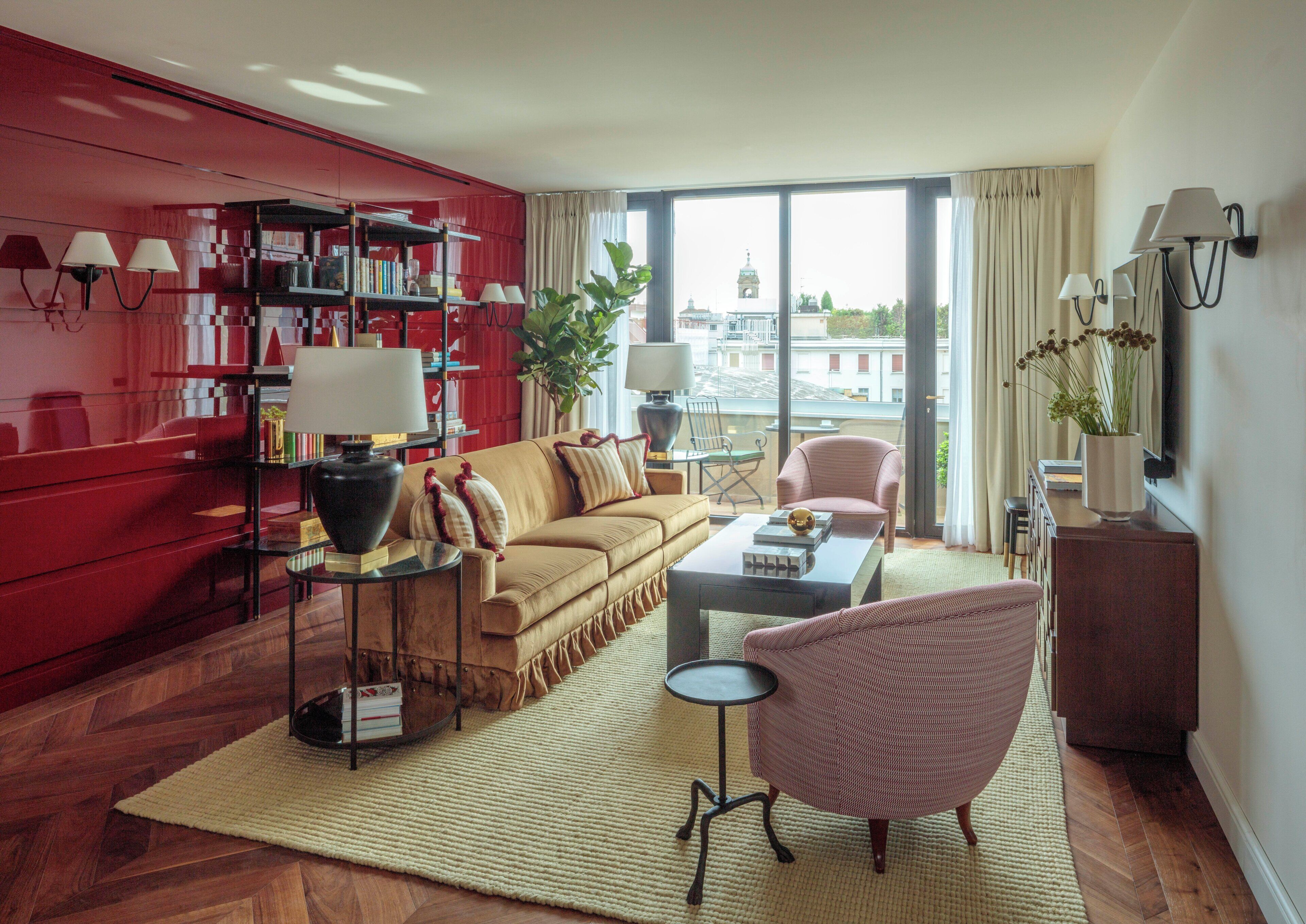 A modern living room with a red bookshelf, a beige sofa, a coffee table, and a pink armchair.