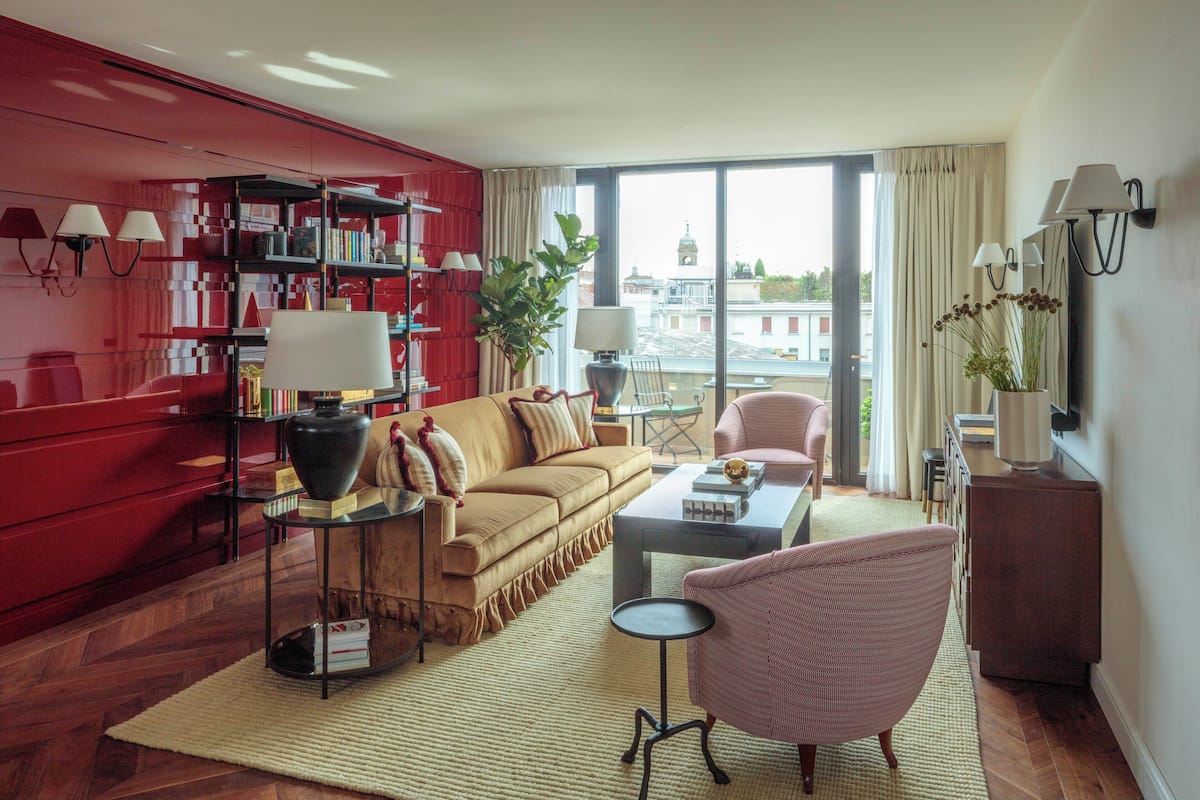 A modern living room with a red bookshelf, a beige sofa, a coffee table, and a pink armchair.