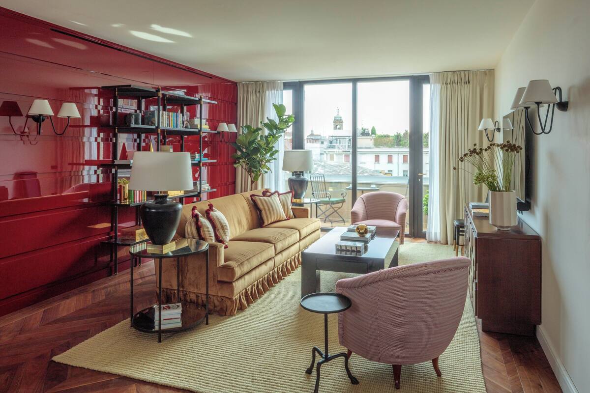 Un salon moderne avec une bibliothèque rouge, un canapé beige, une table basse et un fauteuil rose.