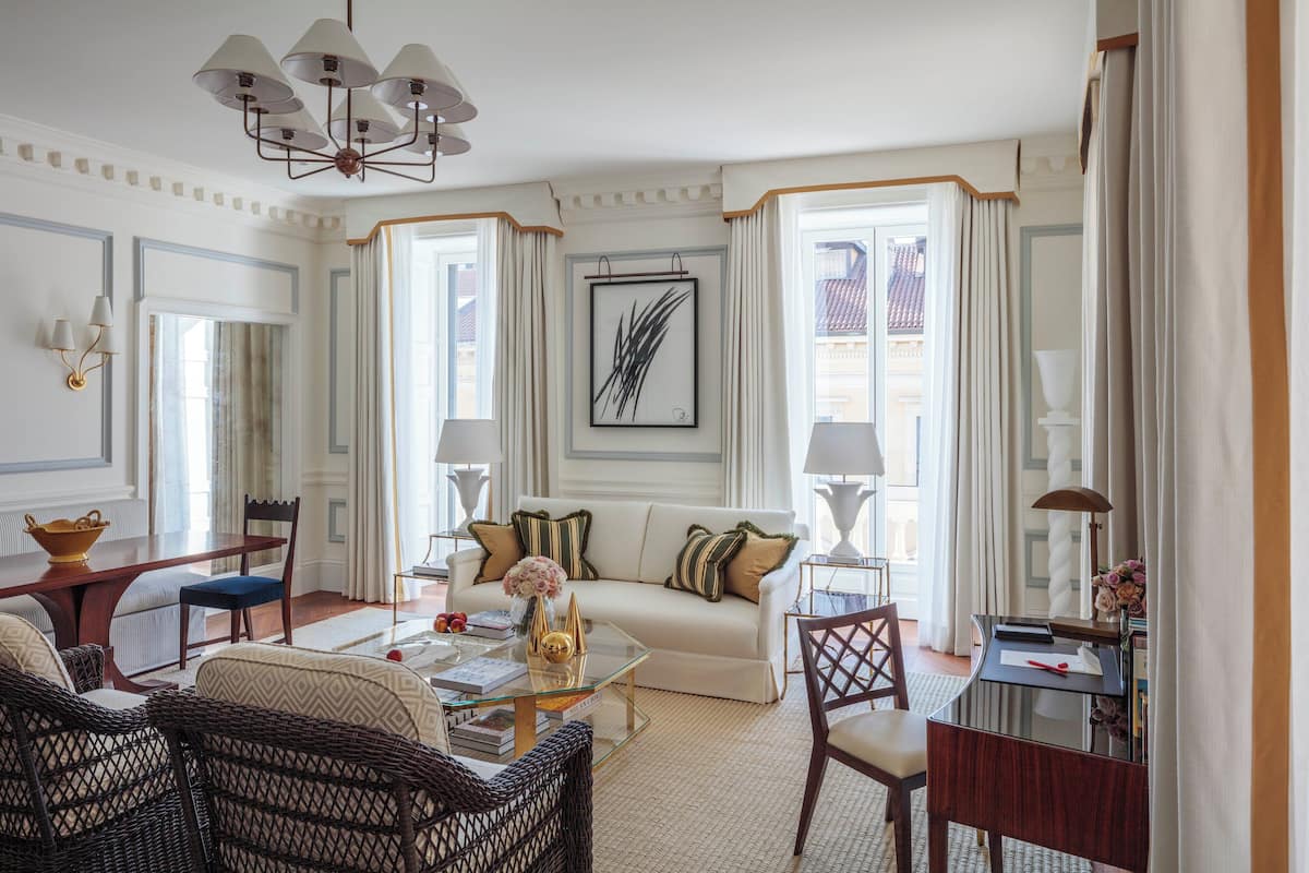 A well-lit, elegantly furnished living room with a sofa, chairs, a coffee table, and a dining area.