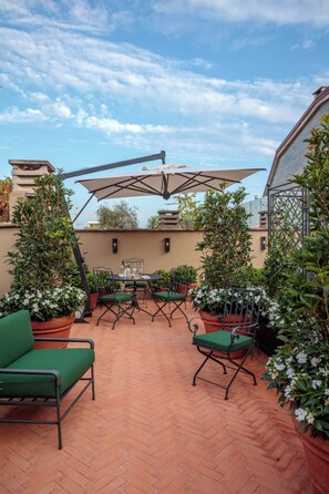 An outdoor patio with terracotta flooring, green cushioned chairs, and potted plants. - Rocco Forte House Via Manzoni Milan (Milan)