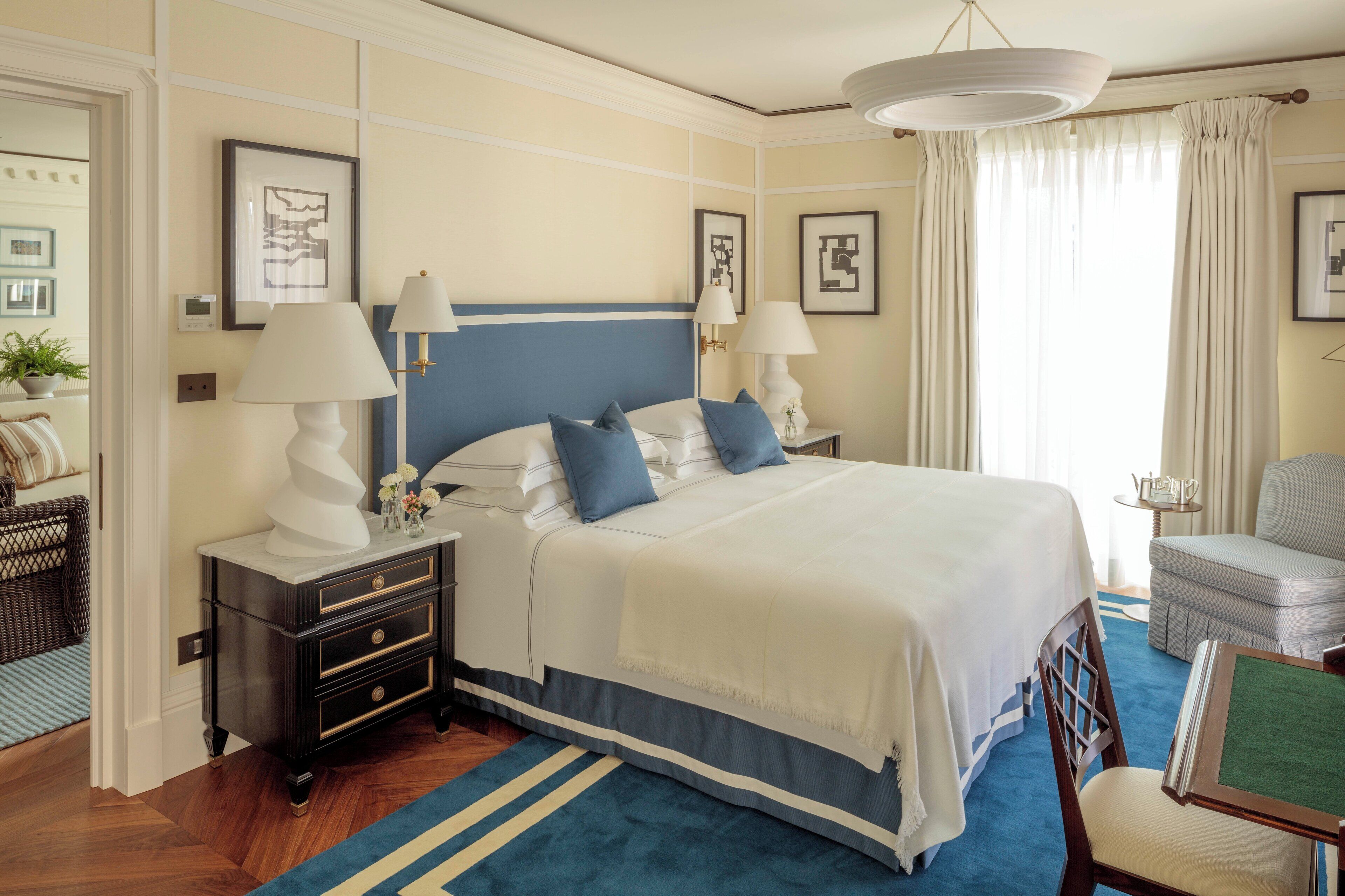 A neatly arranged bedroom with a large bed, bedside tables, a chair, and a small table.