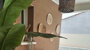 Una panchina di legno con cuscini, un cesto di vimini e una pianta in vaso su un balcone con vista su una piscina.