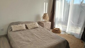 Una camera da letto con un letto grande, una lampada da comodino e vista all'esterno attraverso tende leggere.