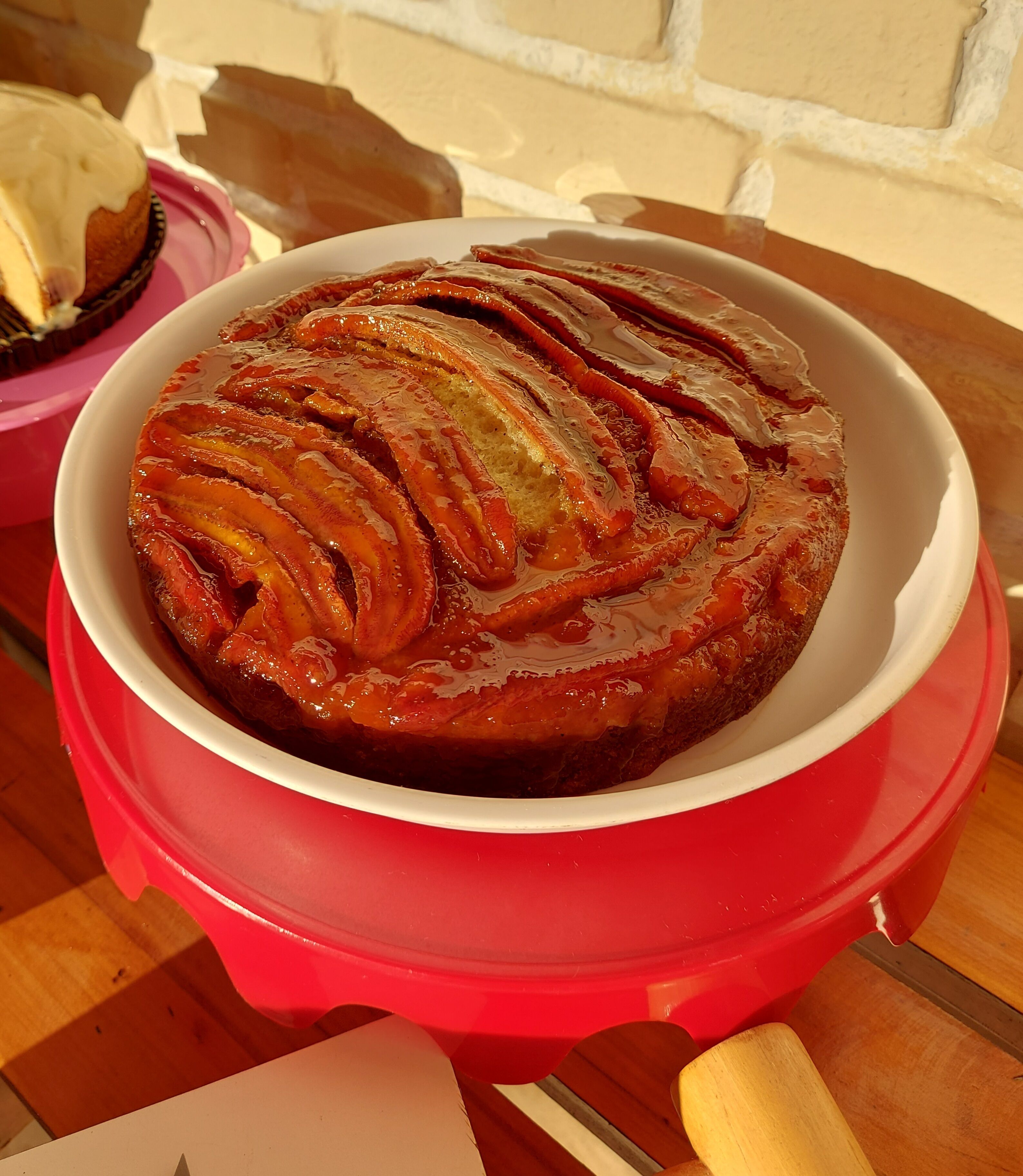 A red pot with a glazed baked dish on a wooden table.
