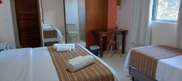 Habitación de hotel con dos camas, un escritorio, una silla, un inodoro y una ducha.