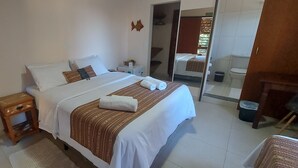 Ein ordentlich eingerichtetes Schlafzimmer mit Bett, Nachttisch und einem Spiegel, der das Badezimmer widerspiegelt.