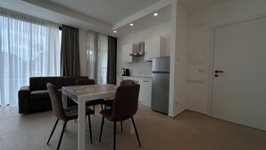 A modern kitchen with a refrigerator, stove, and cabinets. There is a dining area with a table and chairs. - Puglia Promenade Apartment 4 (Bari)