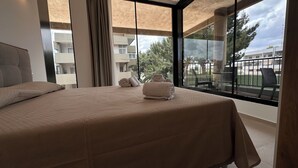 A hotel room with a large bed, a view of the outdoor balcony, and a window with curtains. - Puglia Promenade Apartment 4 (Bari)