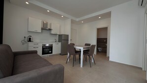 A modern kitchen with white cabinets, a built-in oven, and a refrigerator. There is a dining table with four chairs. - Puglia Promenade Apartment 4 (Bari)