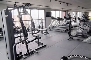 A modern gym with cardio machines, weightlifting equipment, and dumbbells. - Charmosos Studios no coração de Sampa (São Paulo)