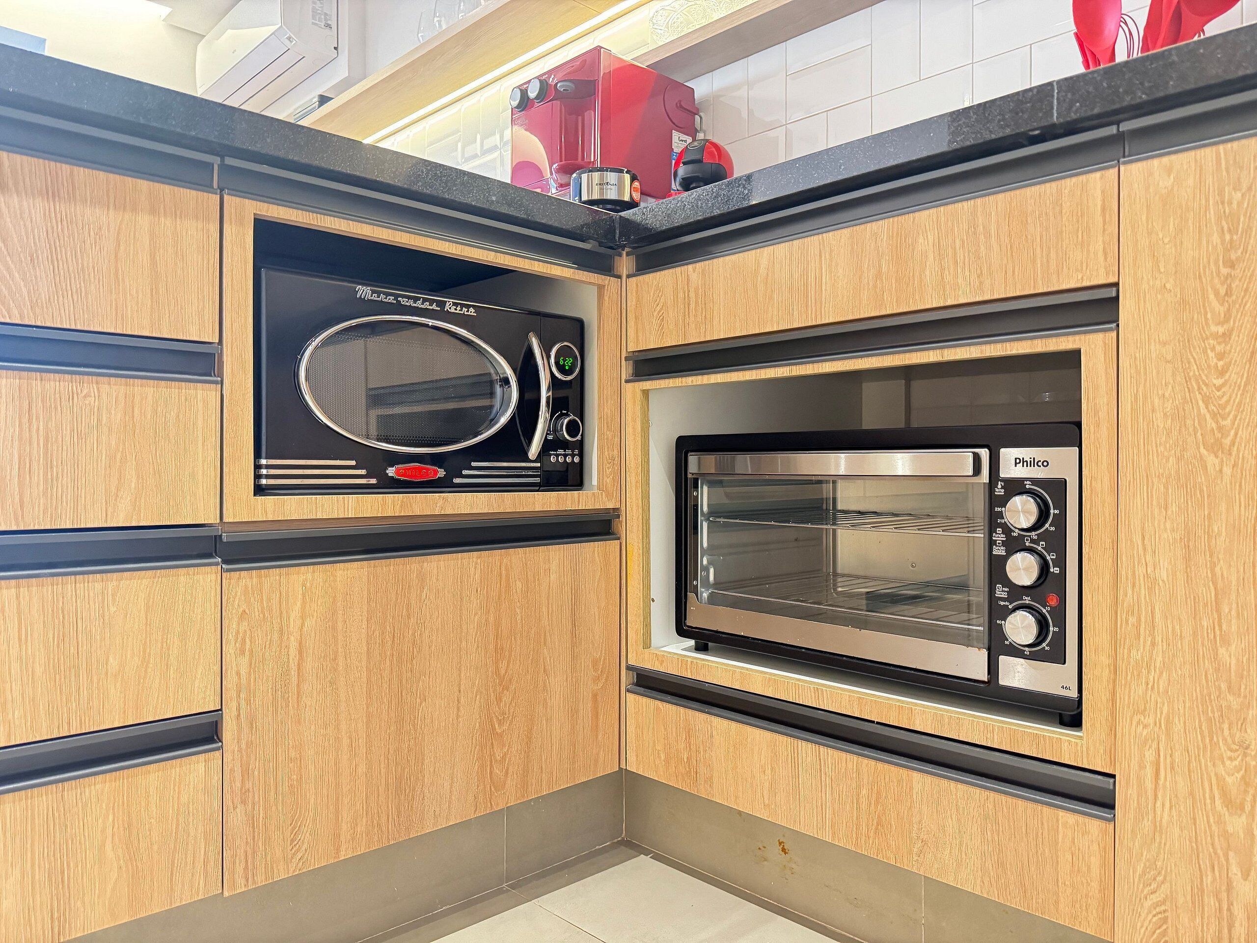 Een keuken met een magnetron en oven, ingebouwd in houten kastjes.