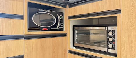 A kitchen with a microwave and an oven built into wooden cabinetry.