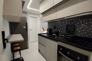 Ett modernt kök med svart kakel som stänkskydd, rostfria vitvaror och en stilren design.