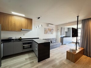 A modern kitchen with grey cabinets, a black countertop, and a built-in oven.