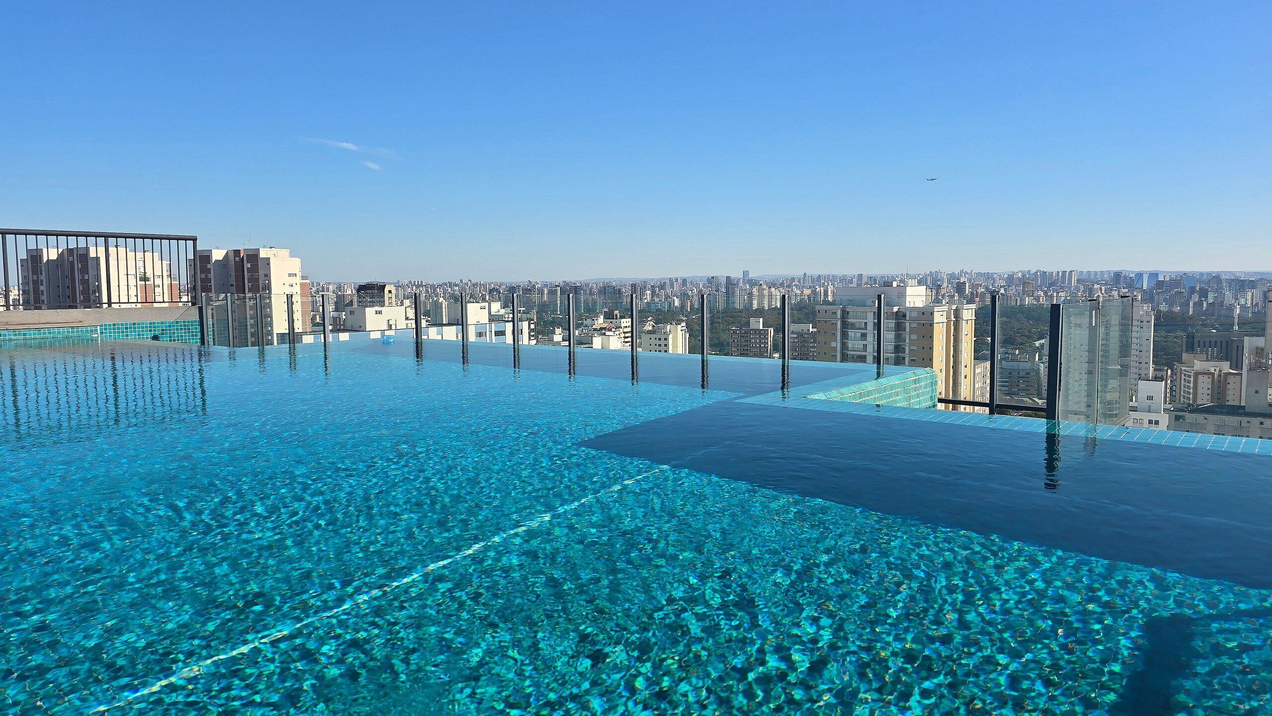 An infinity pool with a cityscape view, clear blue water, and modern buildings in the background.