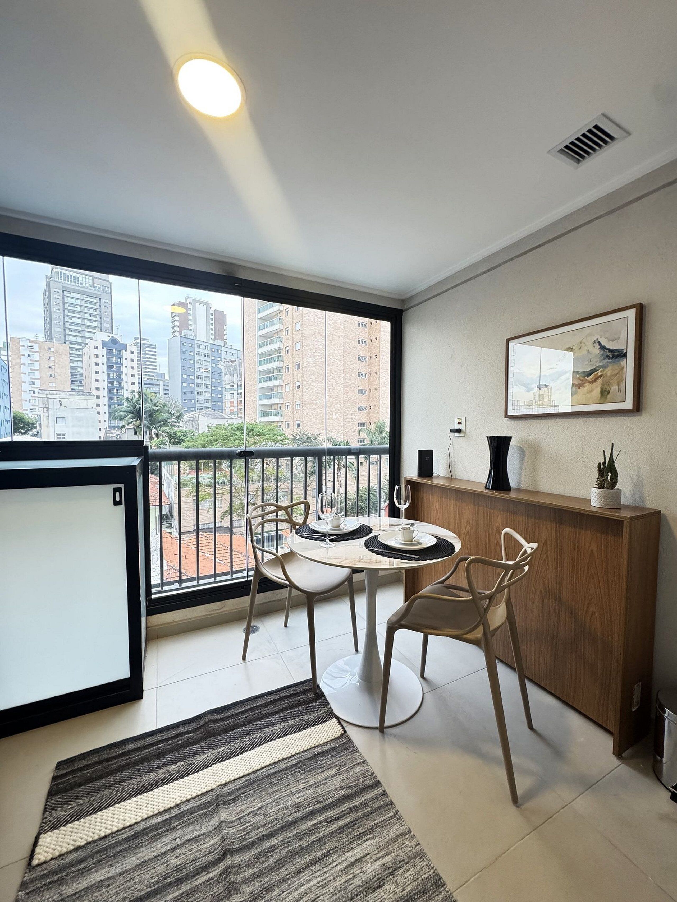 Een modern appartement met balkon, een eethoek en uitzicht op stadsgebouwen.