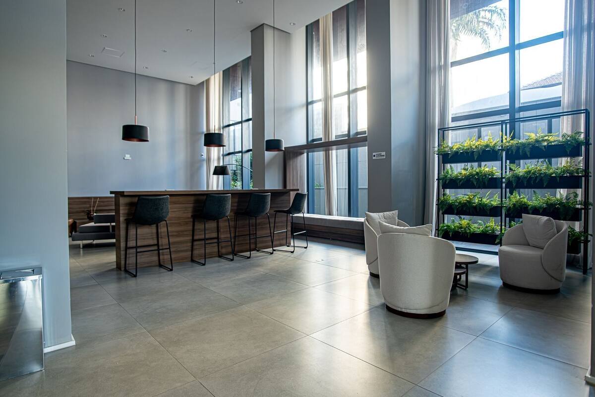 A modern kitchen with a bar area, large windows, and a seating area with a white sofa and chairs.