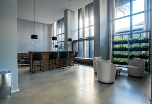 A modern kitchen with a bar area, large windows, and a seating area with a white sofa and chairs.