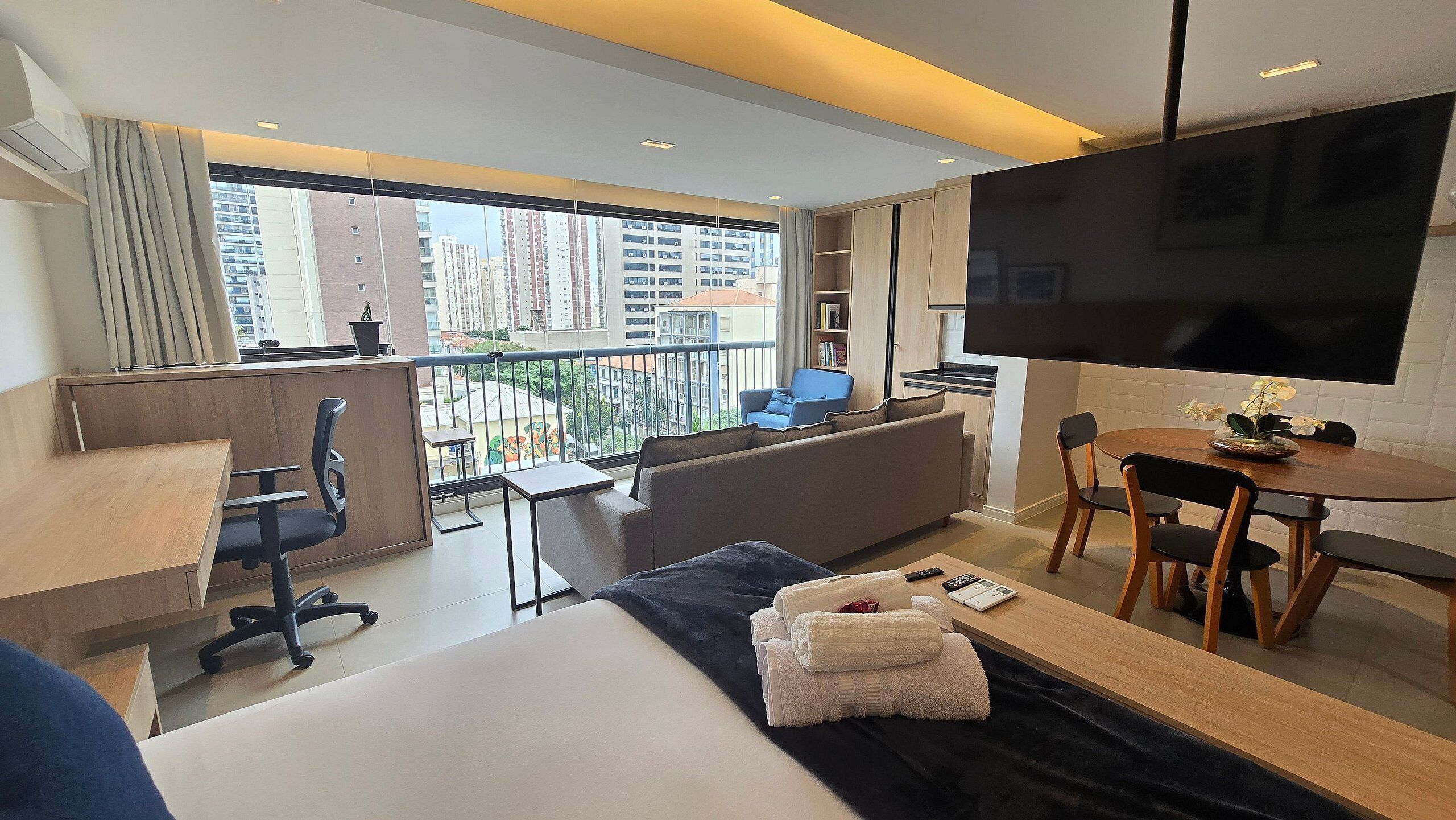 Ein modernes Hotelzimmer mit Balkon, einer Sitzecke, einem Essbereich und einem Fernseher.