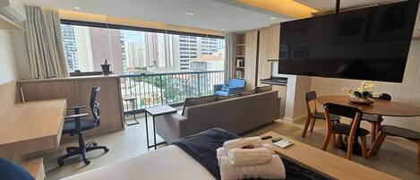Ein modernes Hotelzimmer mit Balkon, einer Sitzecke, einem Essbereich und einem Fernseher.