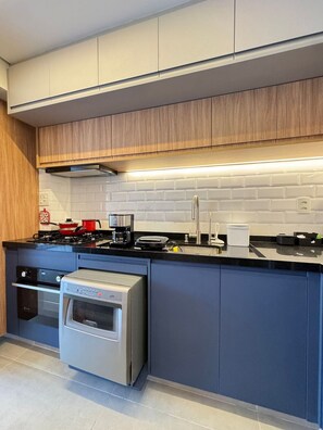 A modern kitchen with a built-in oven, a stovetop, and a coffee maker. - Charmosos Studios no coração de Sampa (São Paulo)