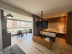 A modern hotel room with a balcony, a bed, a TV, a desk, and a sofa. - Charmosos Studios no coração de Sampa (São Paulo)
