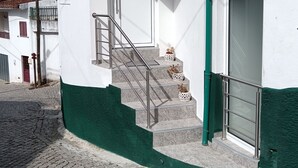 A white building with a green base, a staircase, and a door marked with the number 27. - Casa Fonte do Meio Douro (Armamar)