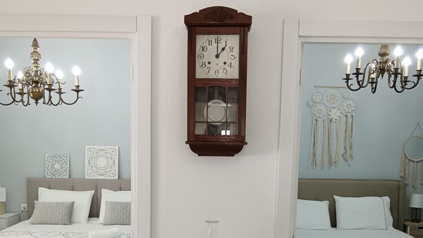 A bedroom with a bed, bedside tables, a wall clock, and a chandelier. - Casa Fonte do Meio Douro (Armamar)