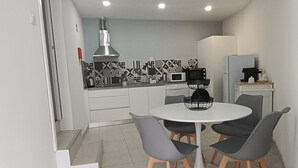 A compact kitchen with a dining area. It includes a stove, microwave, and refrigerator. - Casa Fonte do Meio Douro (Armamar)