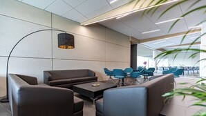 A modern lounge area with sofas, a coffee table, and blue chairs. - A22 Hotel Gyál (Gyal)