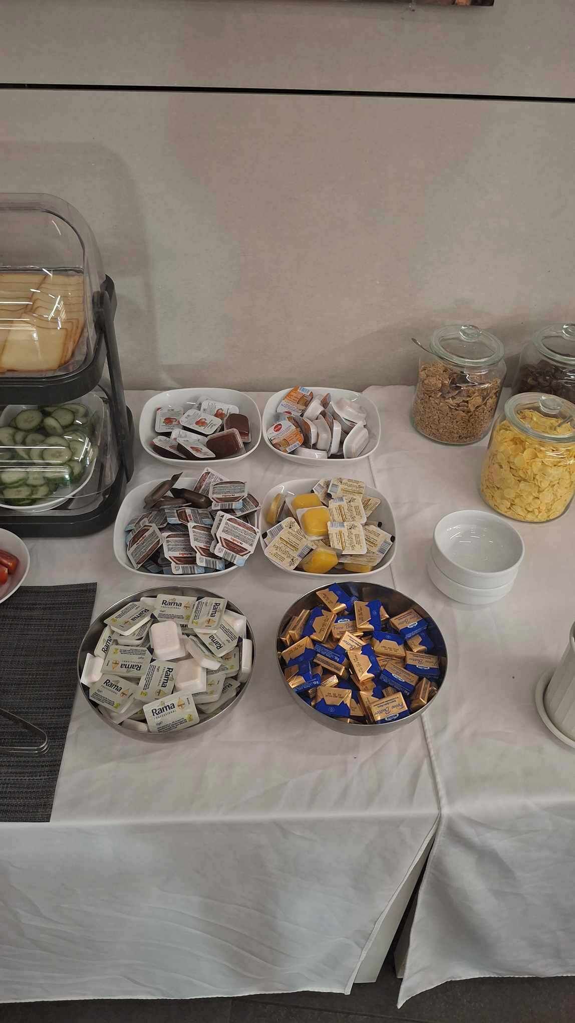 A table with various food items and containers, including jars of cereal and bowls of packaged goods.