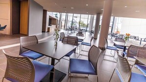A modern dining area with tables and chairs, large windows, and a view of the outside. - A22 Hotel Gyál (Gyal)