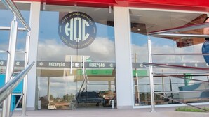 A modern hotel entrance with a glass facade, a red overhang, and a sign reading "HOTEL QUATRO CORÁCES".